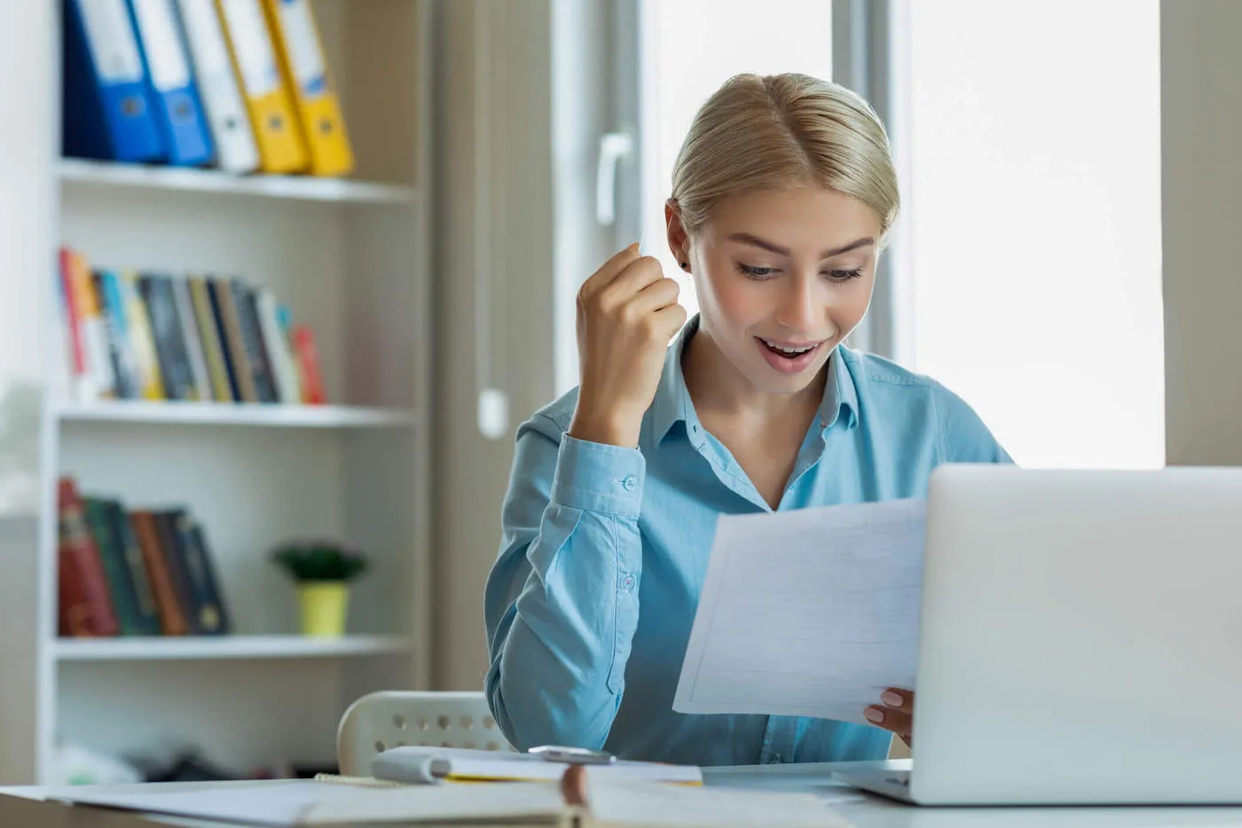 happy woman looking at paper seated at a desk