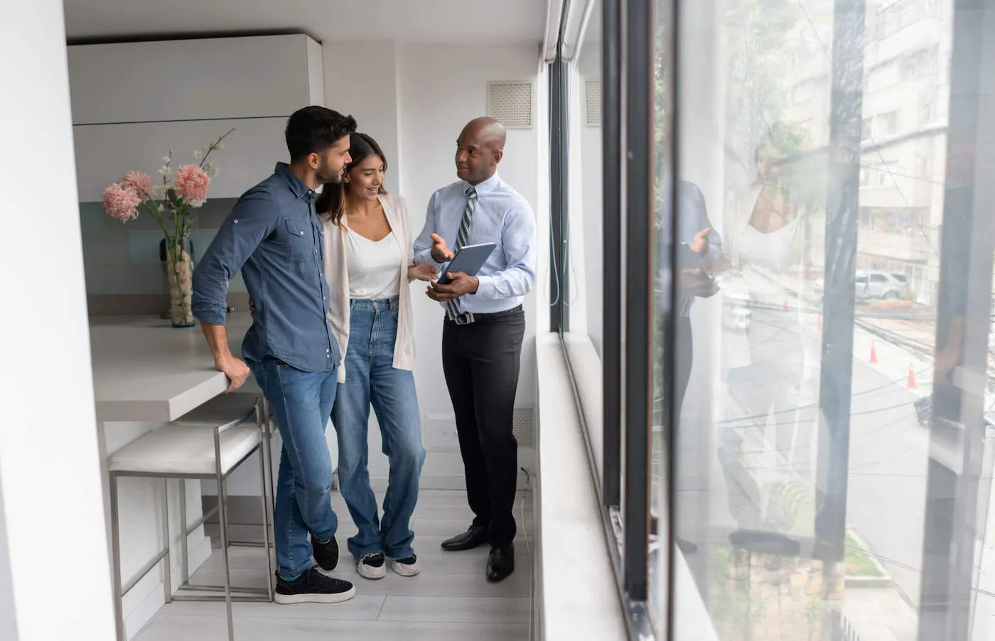 A couple looks at a tablet that is being shown by a realtor in an apartment.