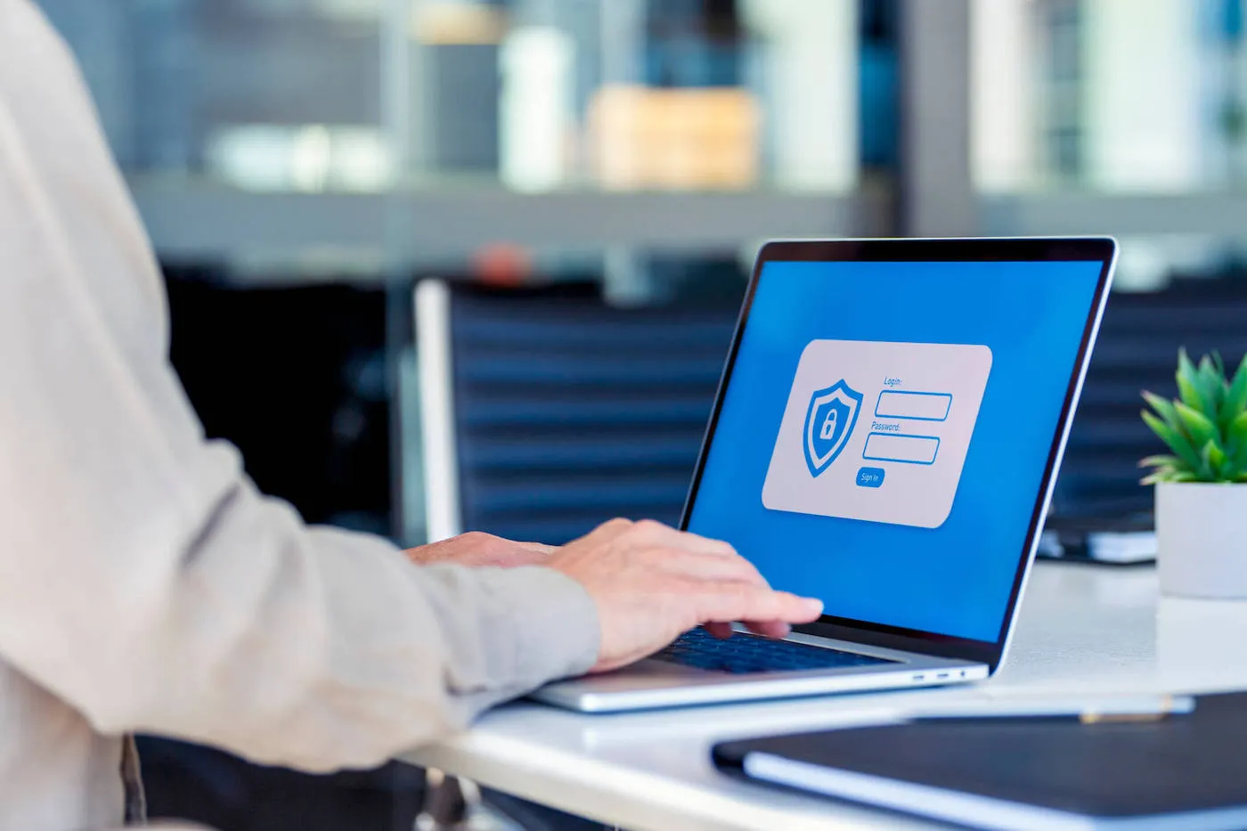 A person types in their login and password on their laptop at the office.