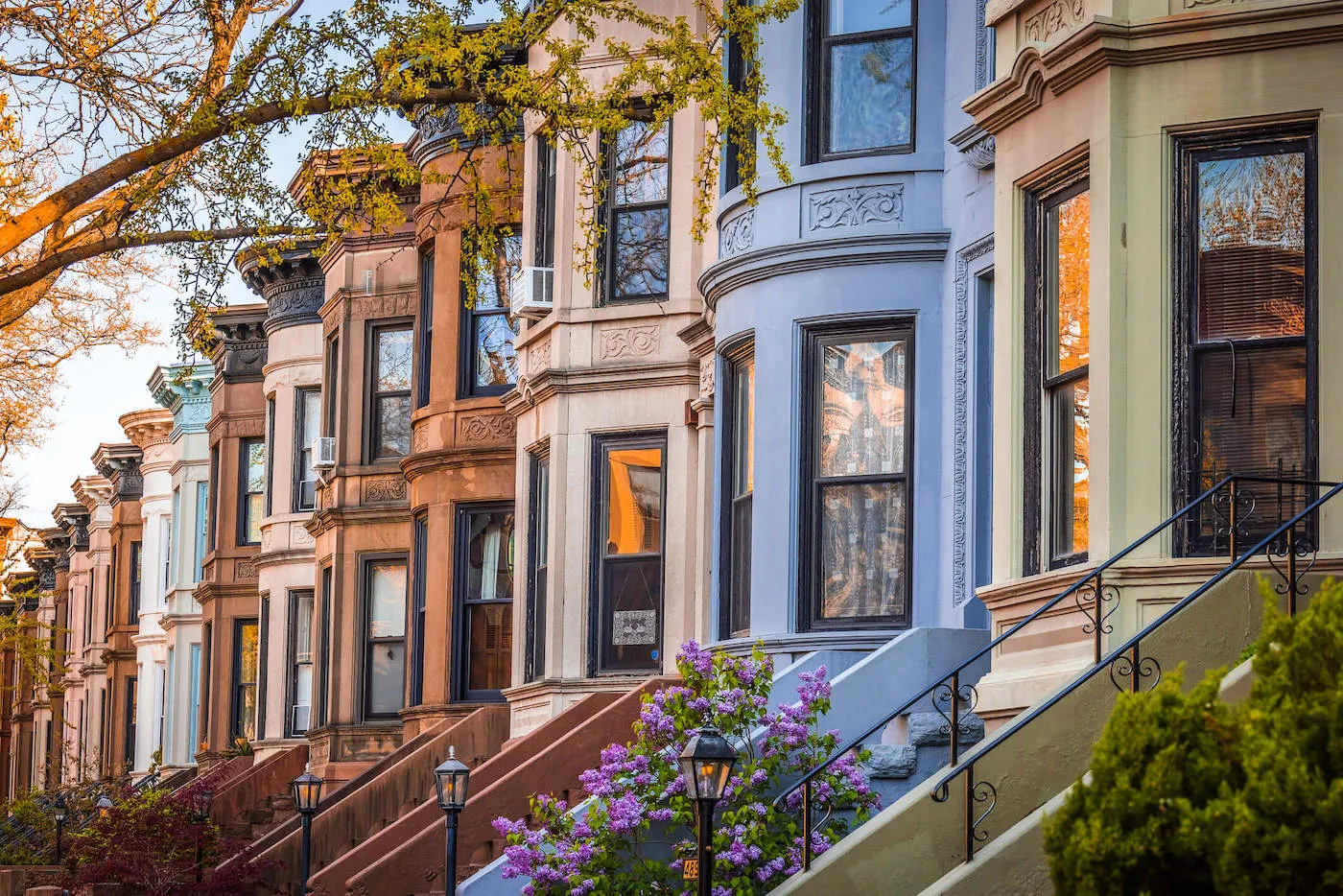 A row of identical victorian homes are lines up in a row with each having different colors.