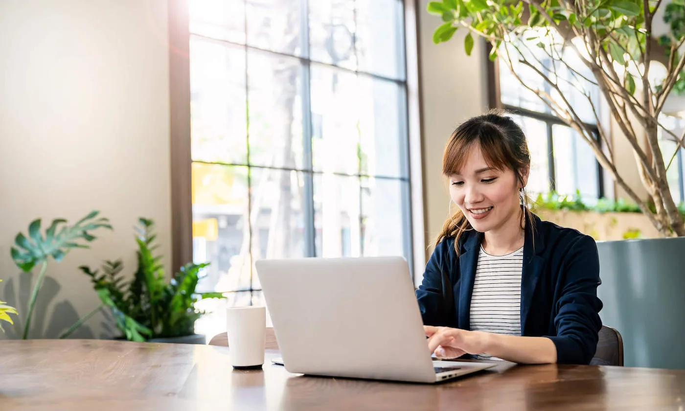 A woman seated at a desk typing on a laptop.