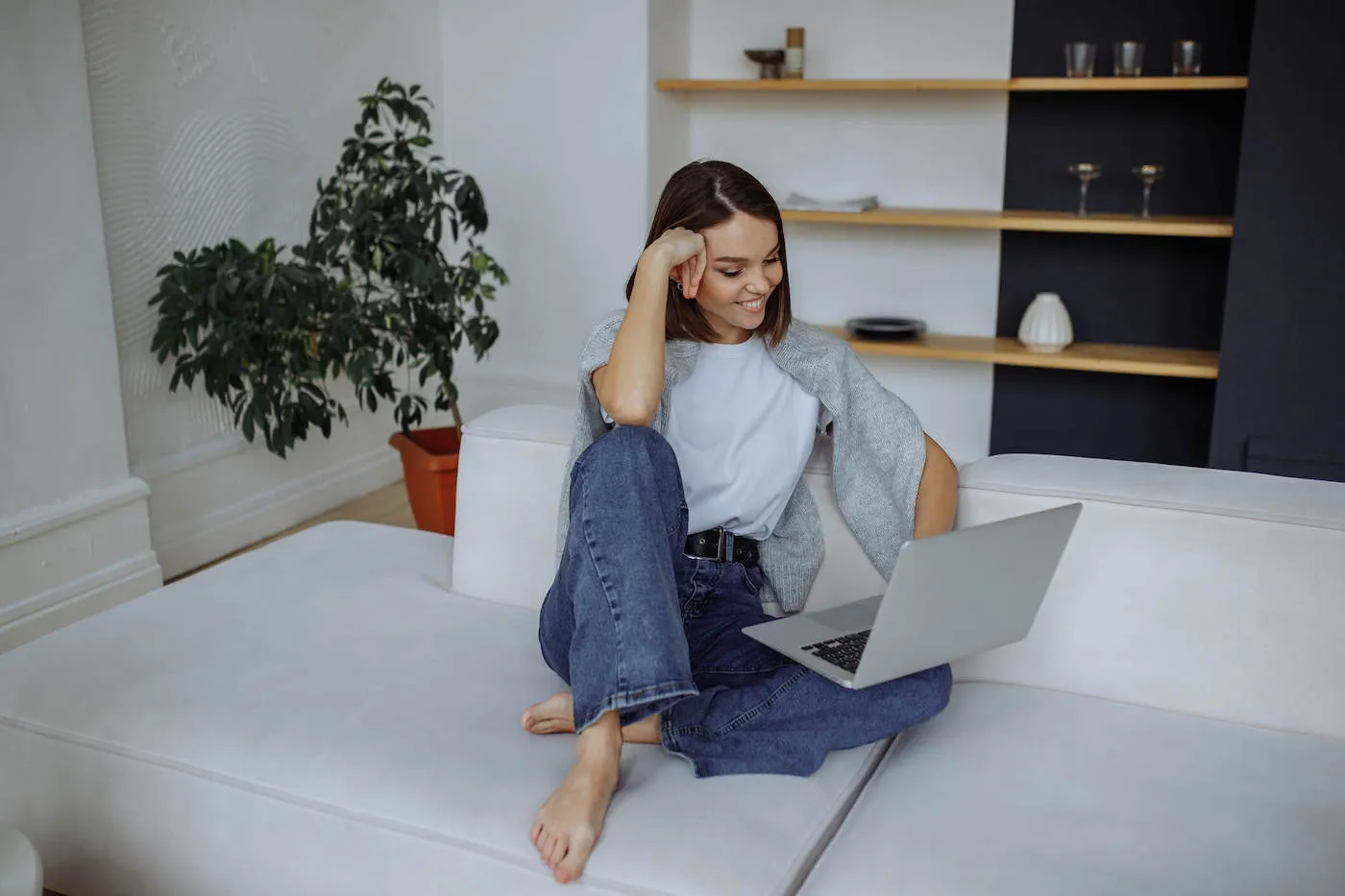 A young girl sits on the sofa at home researching alternatives to balance transfers on a laptop.