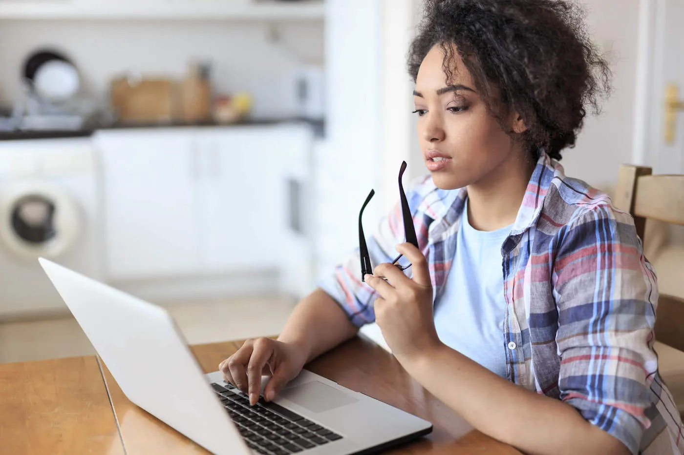 African woman sitting at home and working online on her laptop.