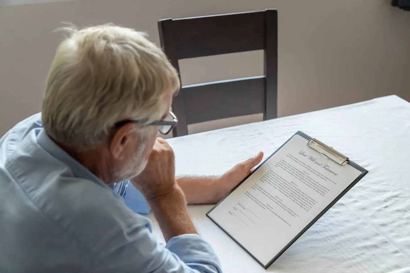 An elderly man looks over his last will and testament document.