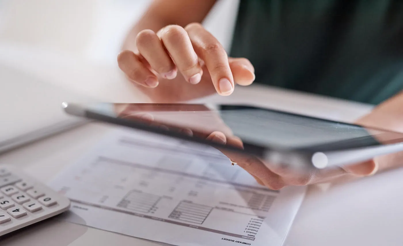 woman typing on a tablet hovering over tax papers