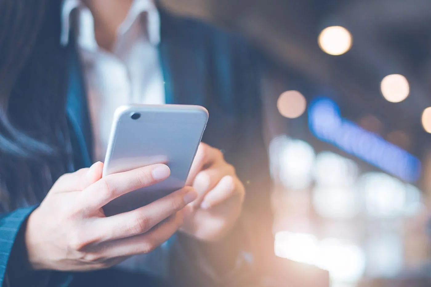 A person wearing a blue suit uses their gray phone.