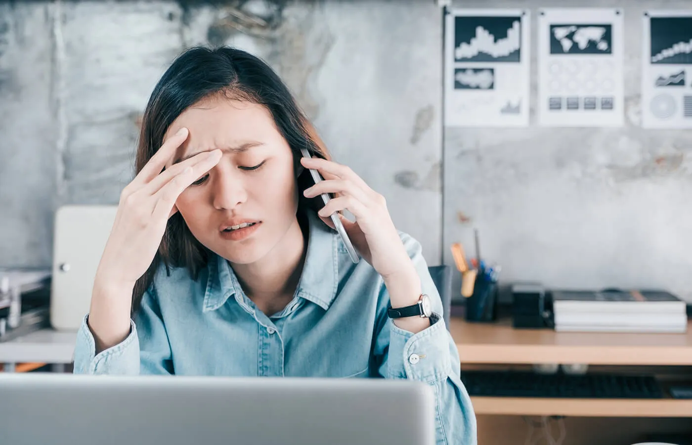 A frustrated woman is making a phone call with an open laptop