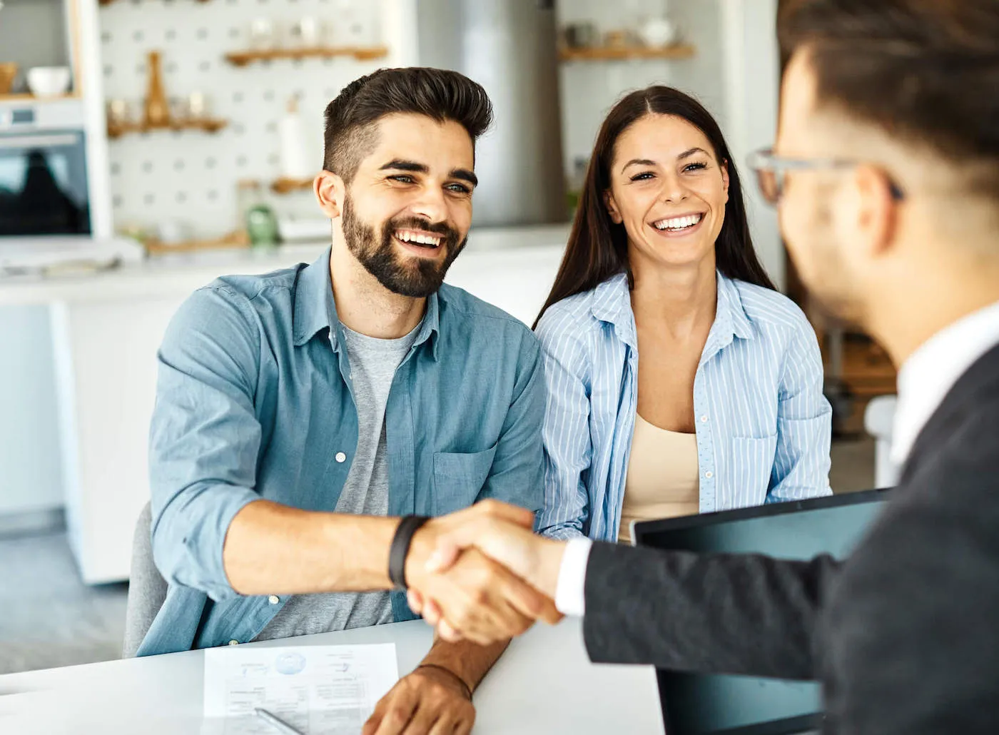 A couple smile at their advisor while the man shakes hands with the other man.