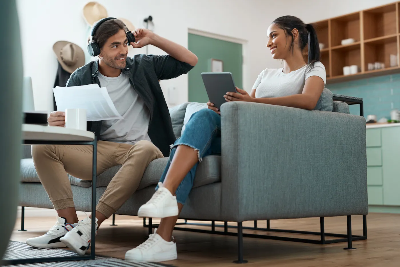 Couple discussing taxes on high yield savings accounts, sitting in living room using a laptop and overear headphones