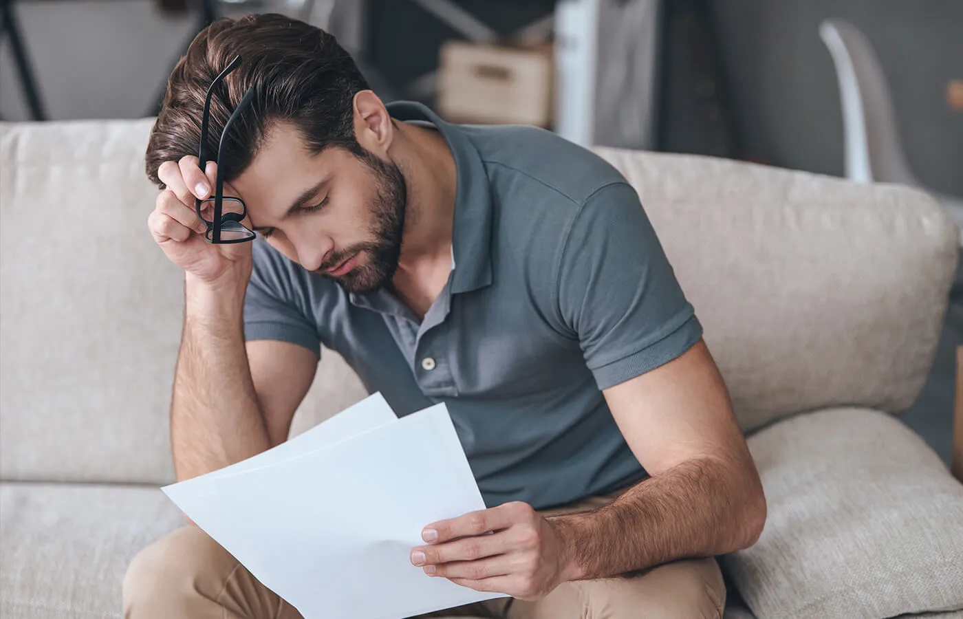 A concerned man looking at his finances on the couch.