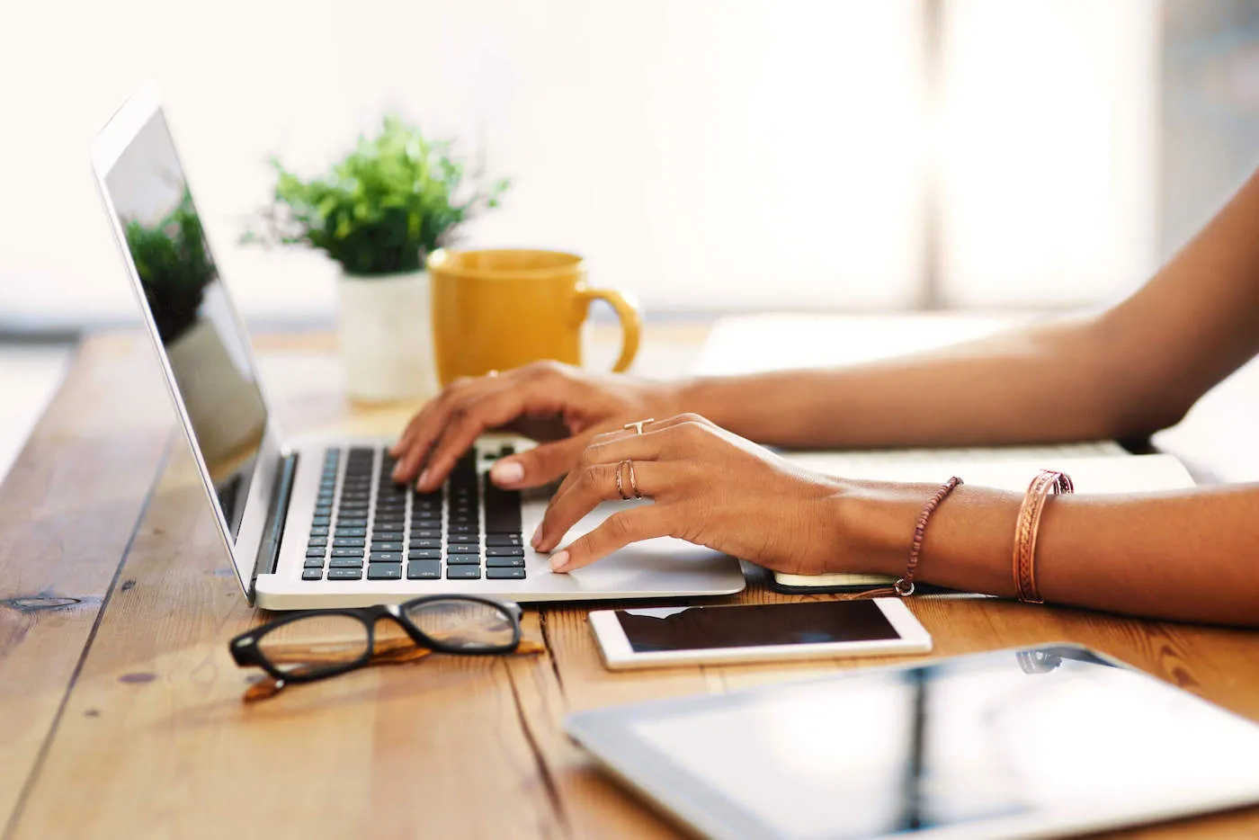 Cropped shot of an unrecognizable businesswoman sitting alone and typing on her laptop during the day at home.