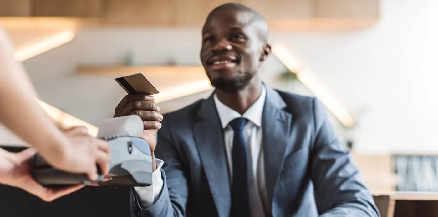 A man in a suit paying for a coffee with his card.