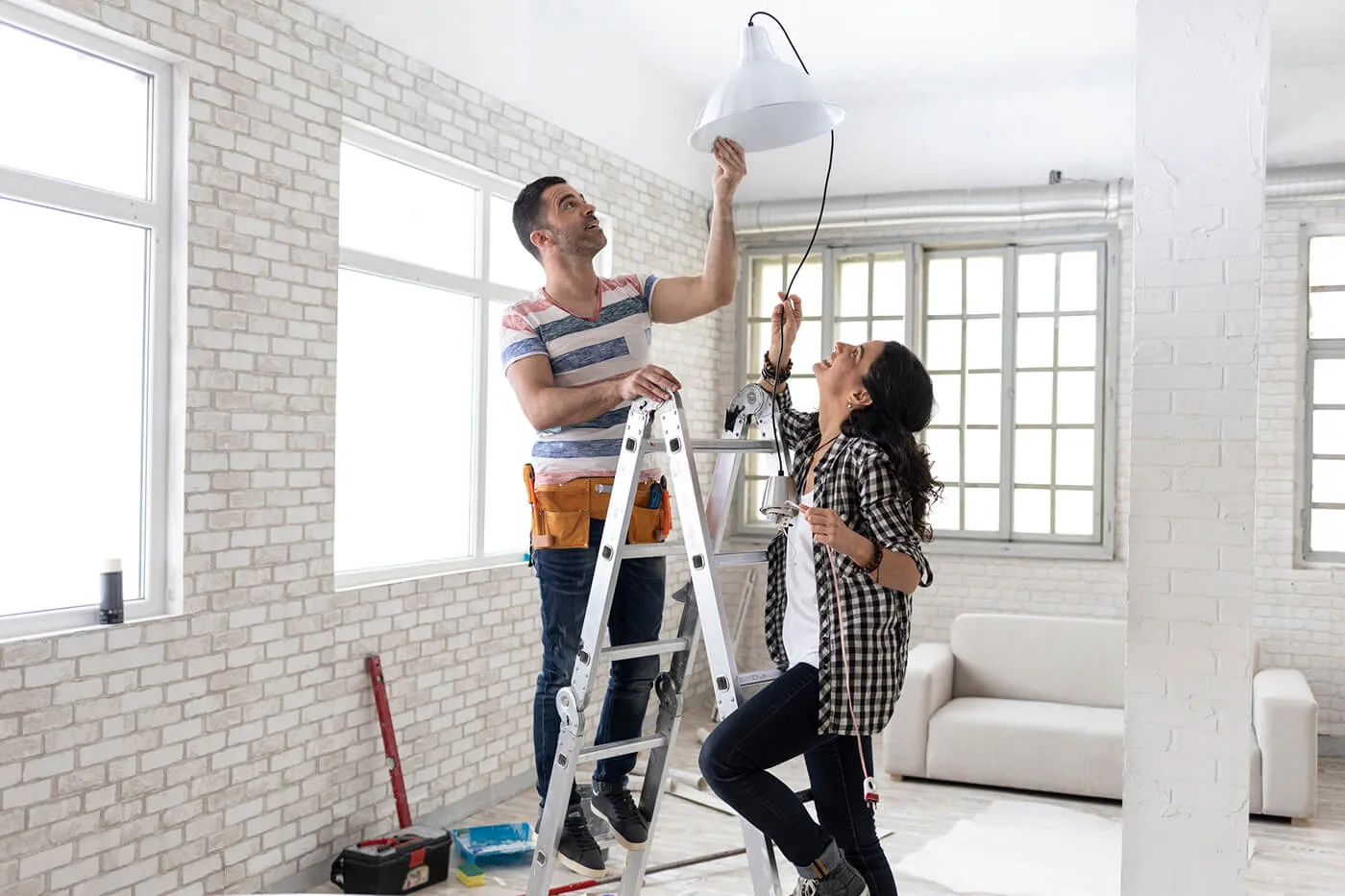 Couple making renovations, changing lighting equipment at home.