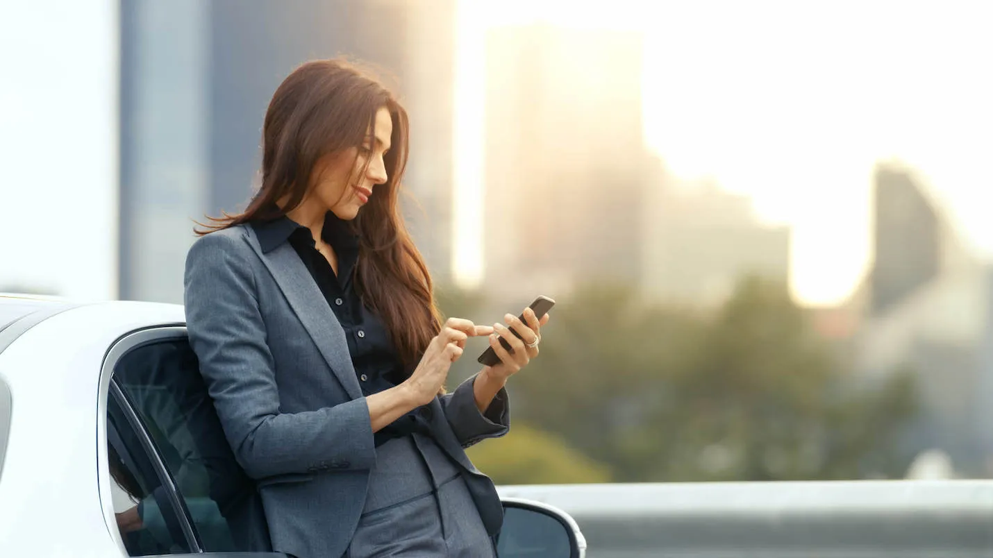 woman in business suit leaning against white car