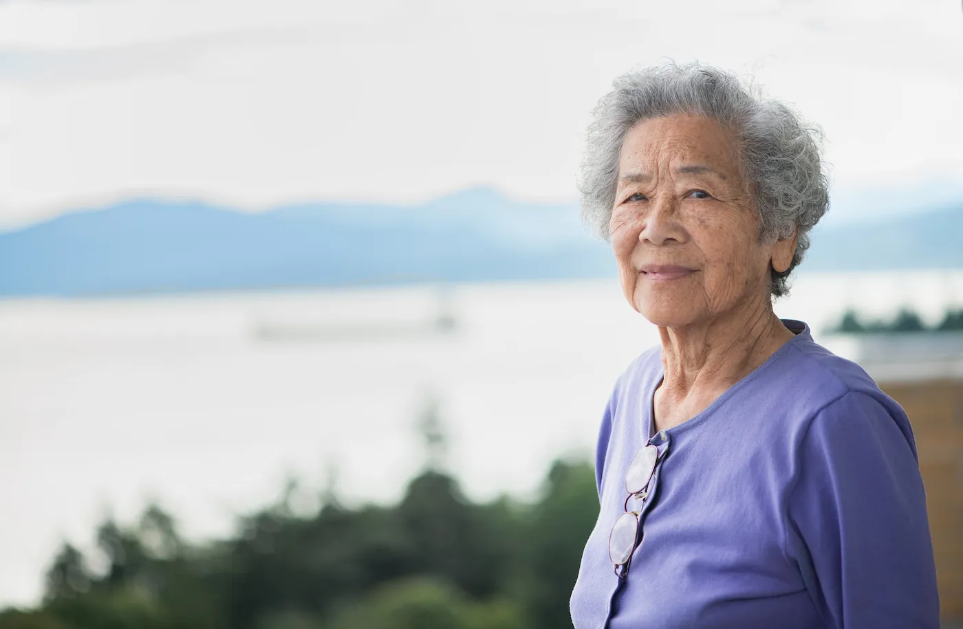 Elderly woman looking out over the water and mountains