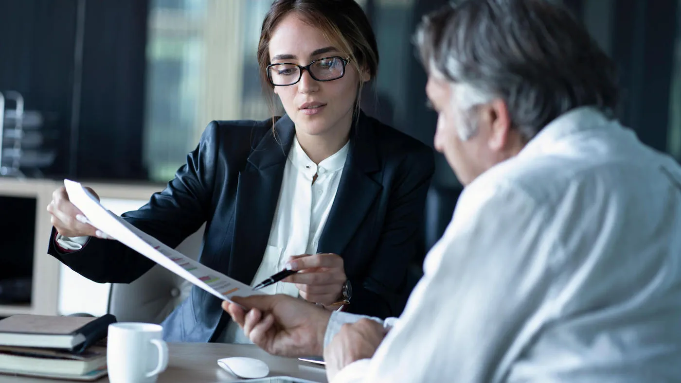 man sitting on a table discussing finances with advisor