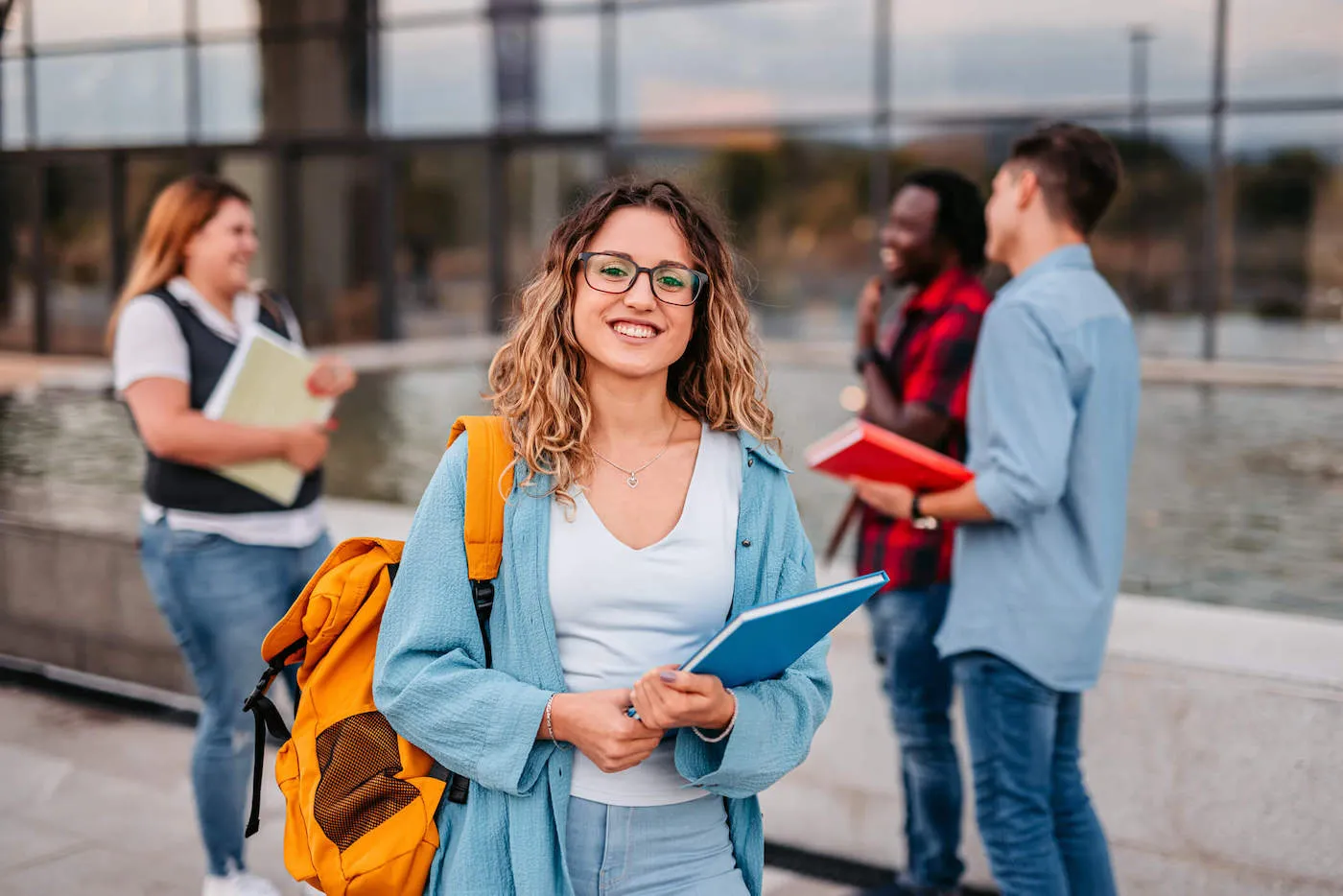 A group of four college students smile while talking with each other in the background.