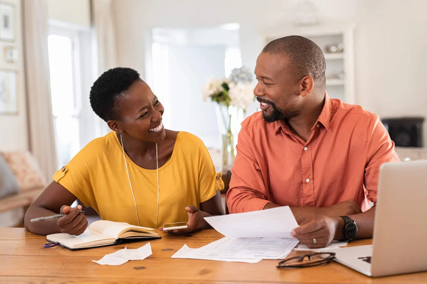 Happy African man and woman paying bills together and managing budget.