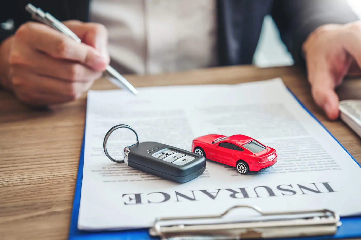 Auto Insurance paper on clipboard with red toy car and car key placed on top