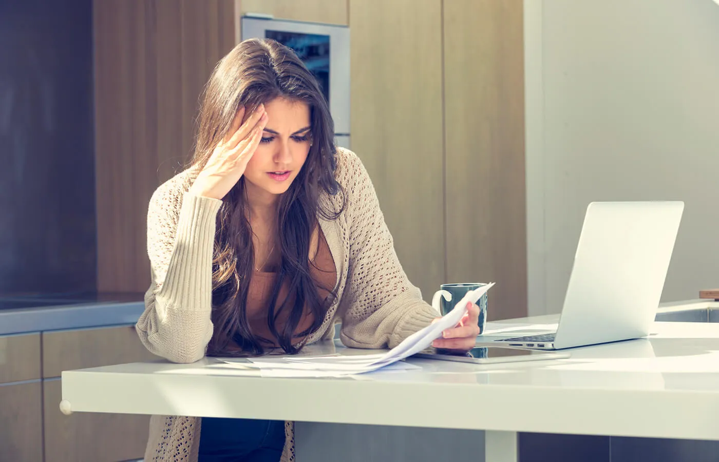 woman in white cardigan looking at paper on white counter