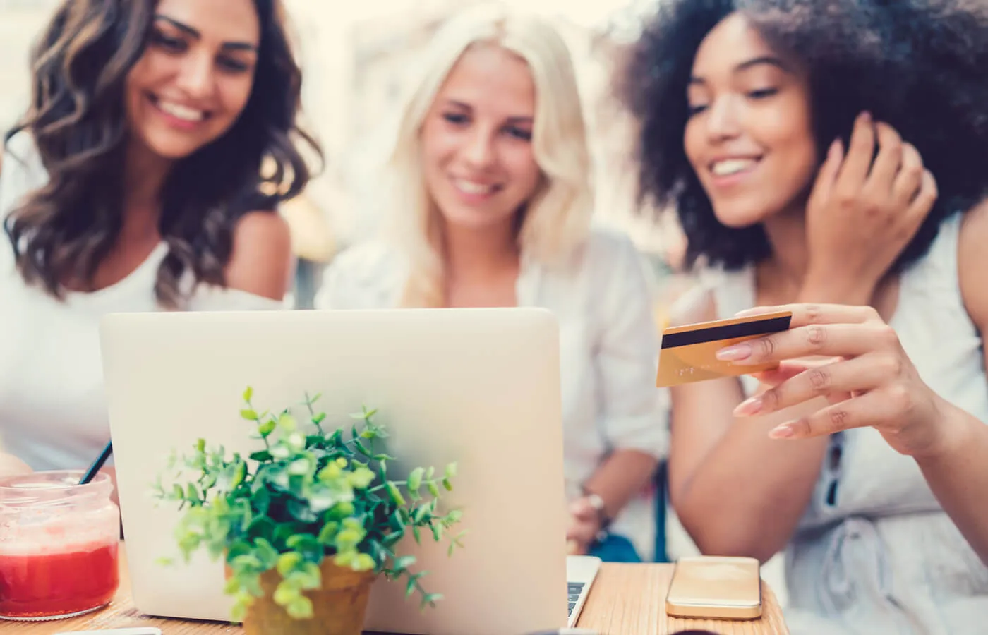 A group of women looking at a laptop. One is holding a credit card.