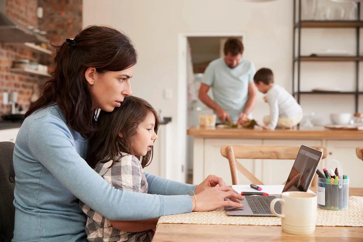 Busy Family Home With Mother Working As Father Prepares Meal