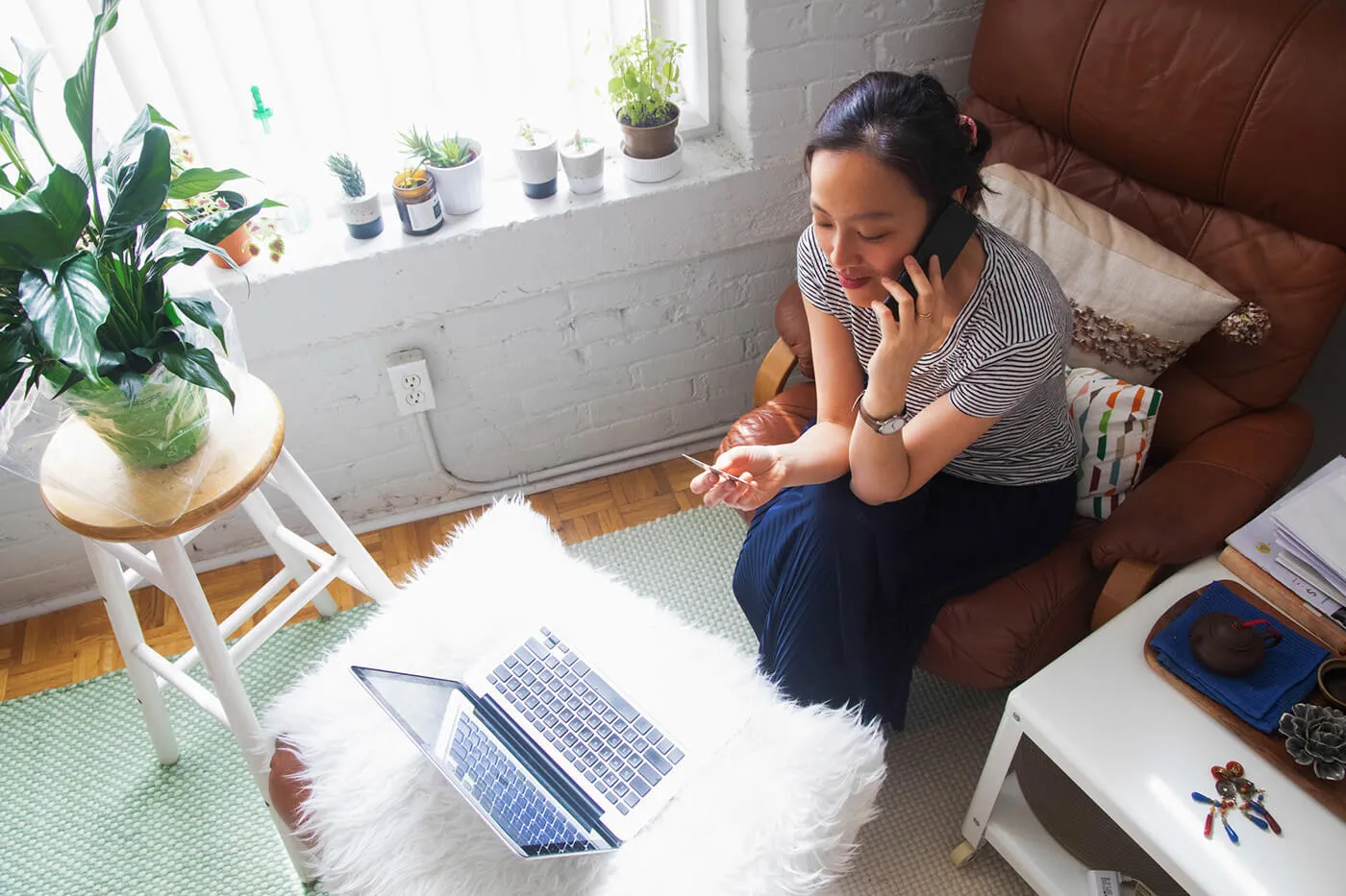 Overhead view of young woman talking to customer service with her credit card in hand