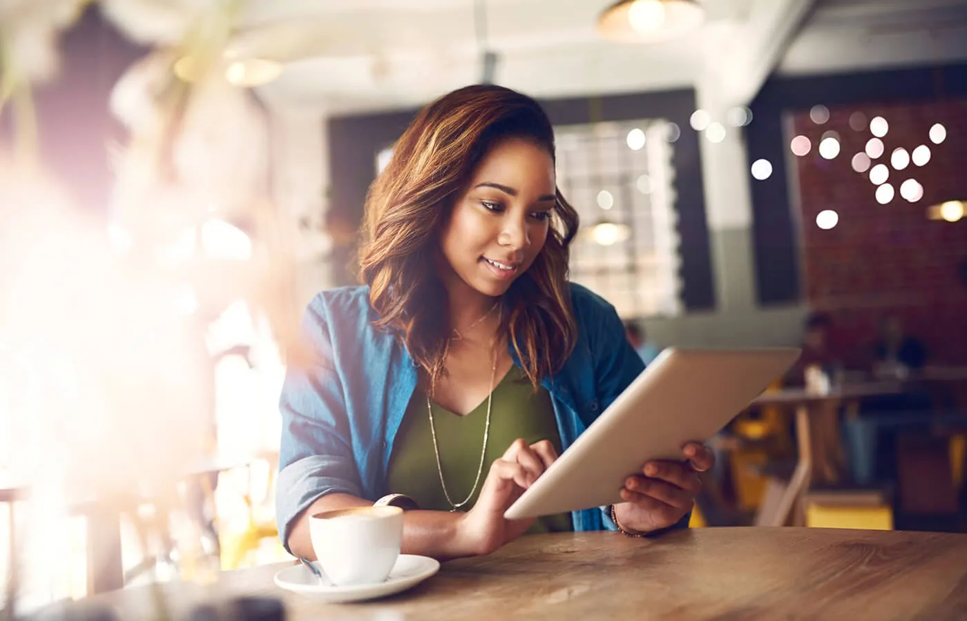 A woman looking at a notepad while sitting in a coffee shop.