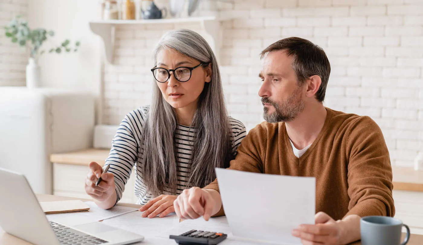 man and woman couple sitting in kitchen looking over papers