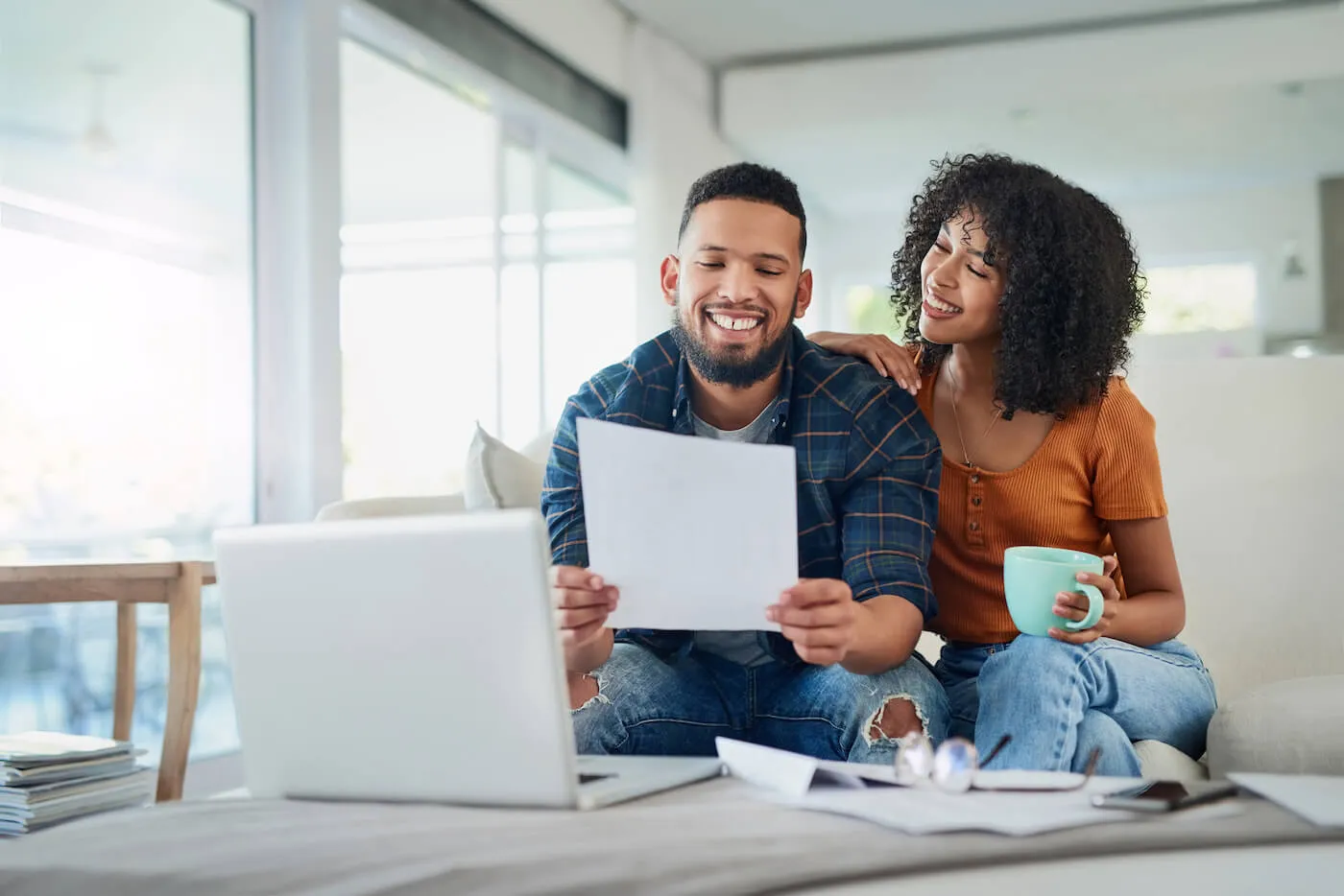 man and woman couple seated in living room looking at medical bill paper