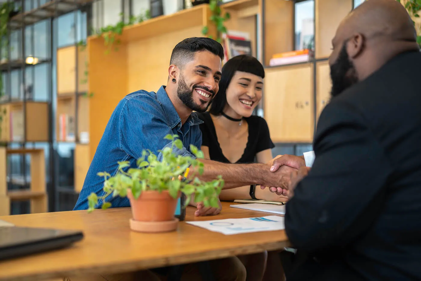 Consultant / Agent and clients on a handshake at business meeting