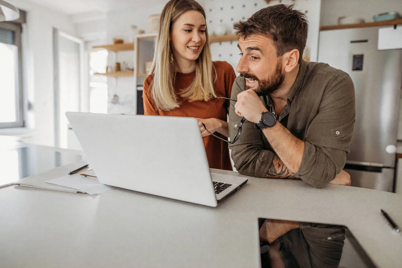 man and woman talking with each other in front of open laptop