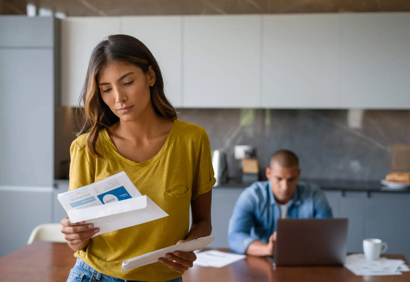 Woman at home looking worried getting bills in the mail.