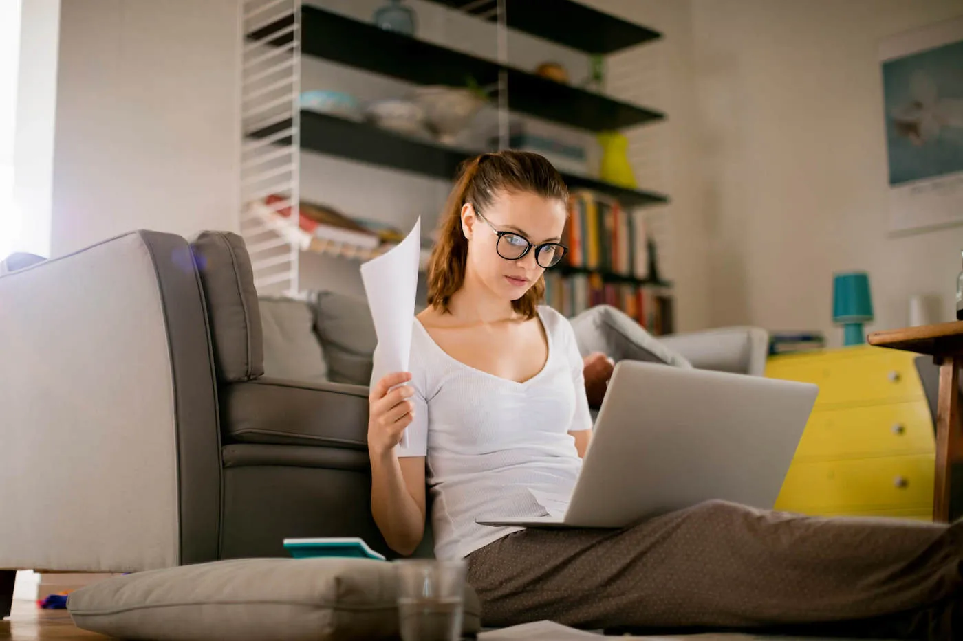 A young woman sitting on the floor and working on laptop.