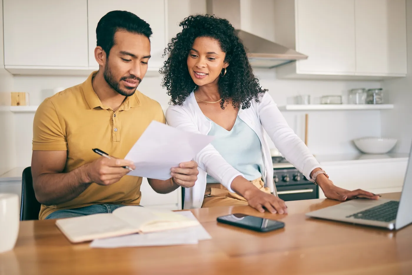 A man and a woman reviewing paperwork together at a kitchen table.