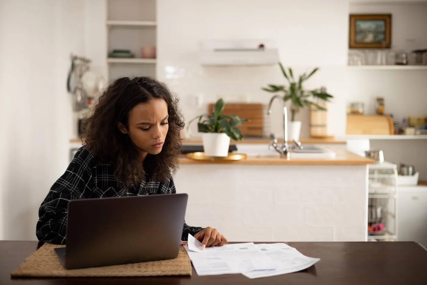 Young woman sorting out her finances at home, using a laptop.