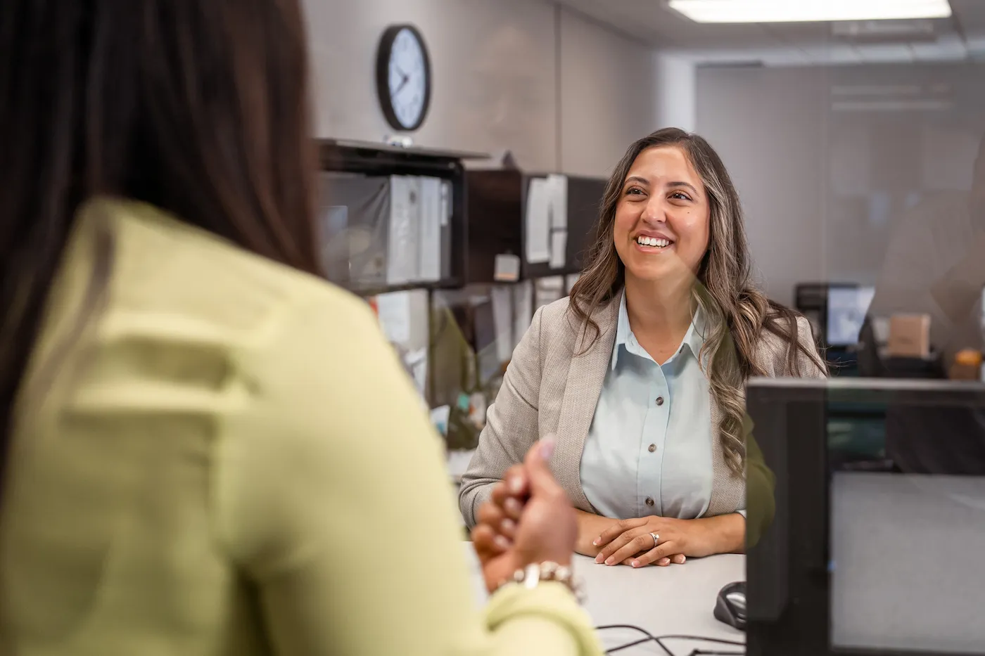 A friendly bank teller helping a customer withdraw her CD early.