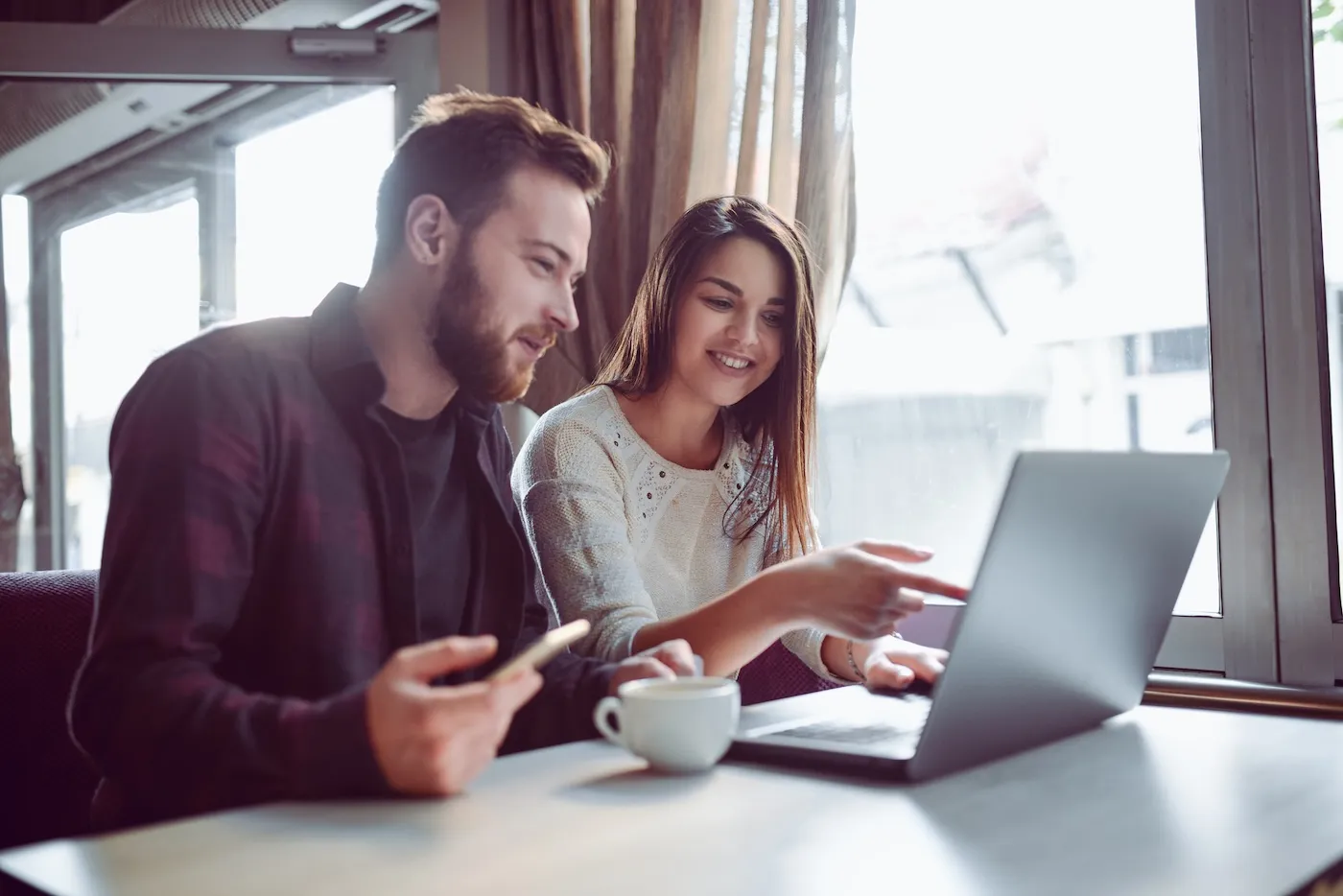 Smiling couple drinking coffee and working on finances in the morning.