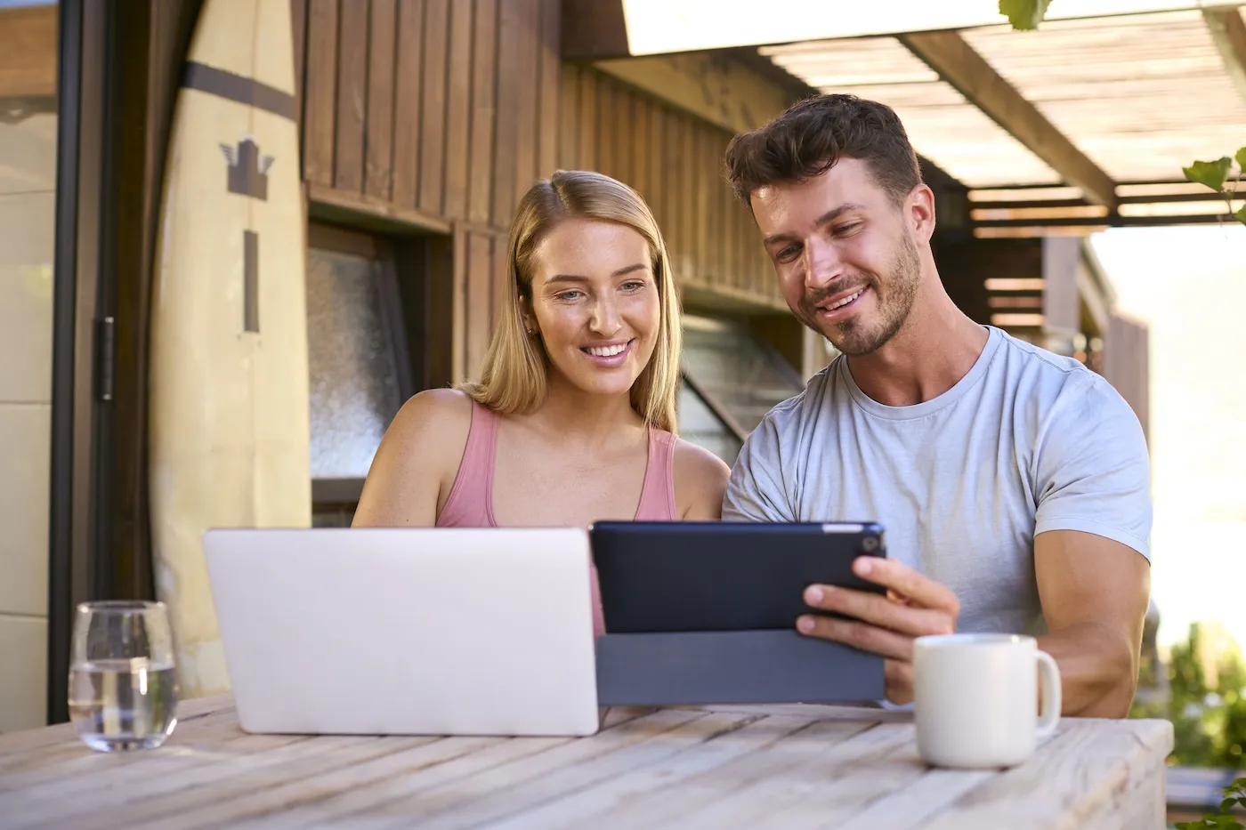 Couple With Laptop And Digital Tablet Outdoors On Table At Home.