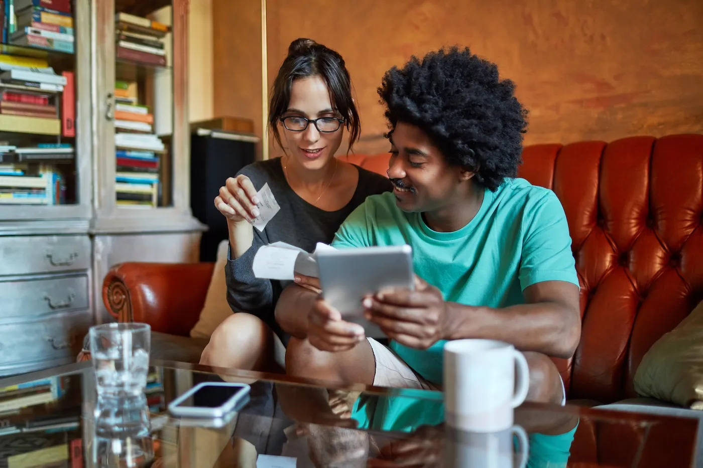 A couple discussing budget over digital tablet and financial bills.