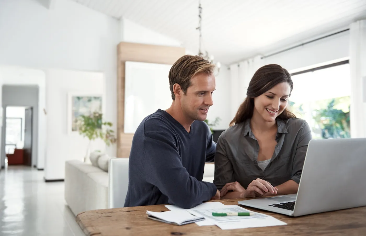 Couple using a laptop together while going through paperwork at home