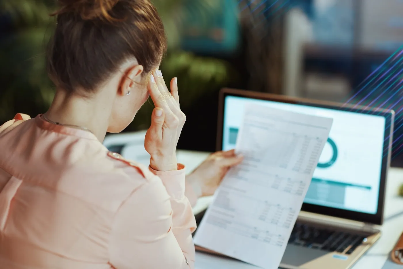 Stressed woman with documents and laptop trying to pay bills.