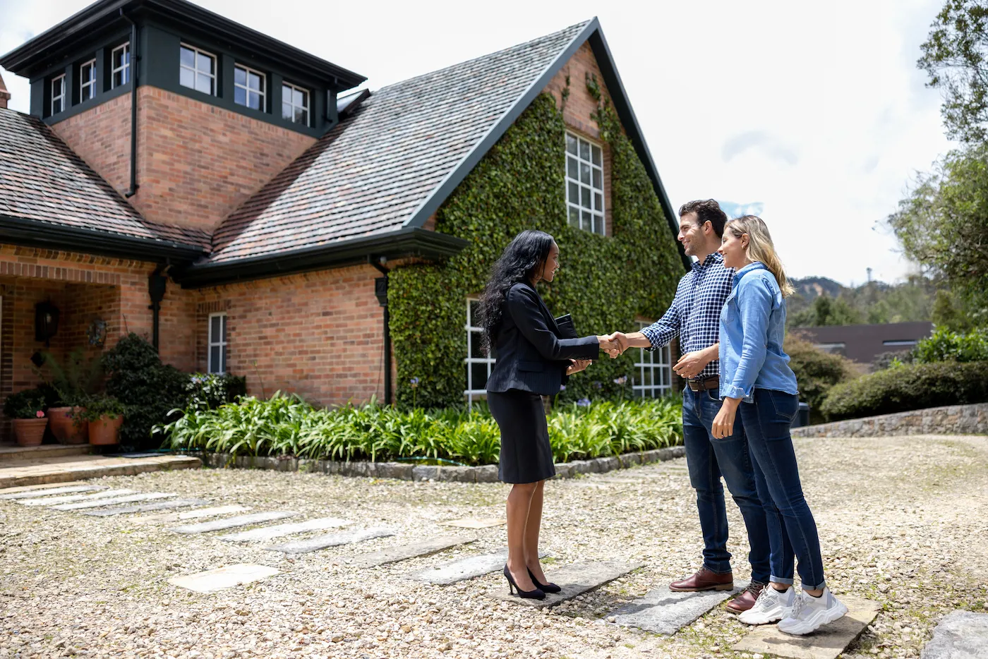 Happy real estate agent meeting a couple for a house showing and greeting them with a handshake