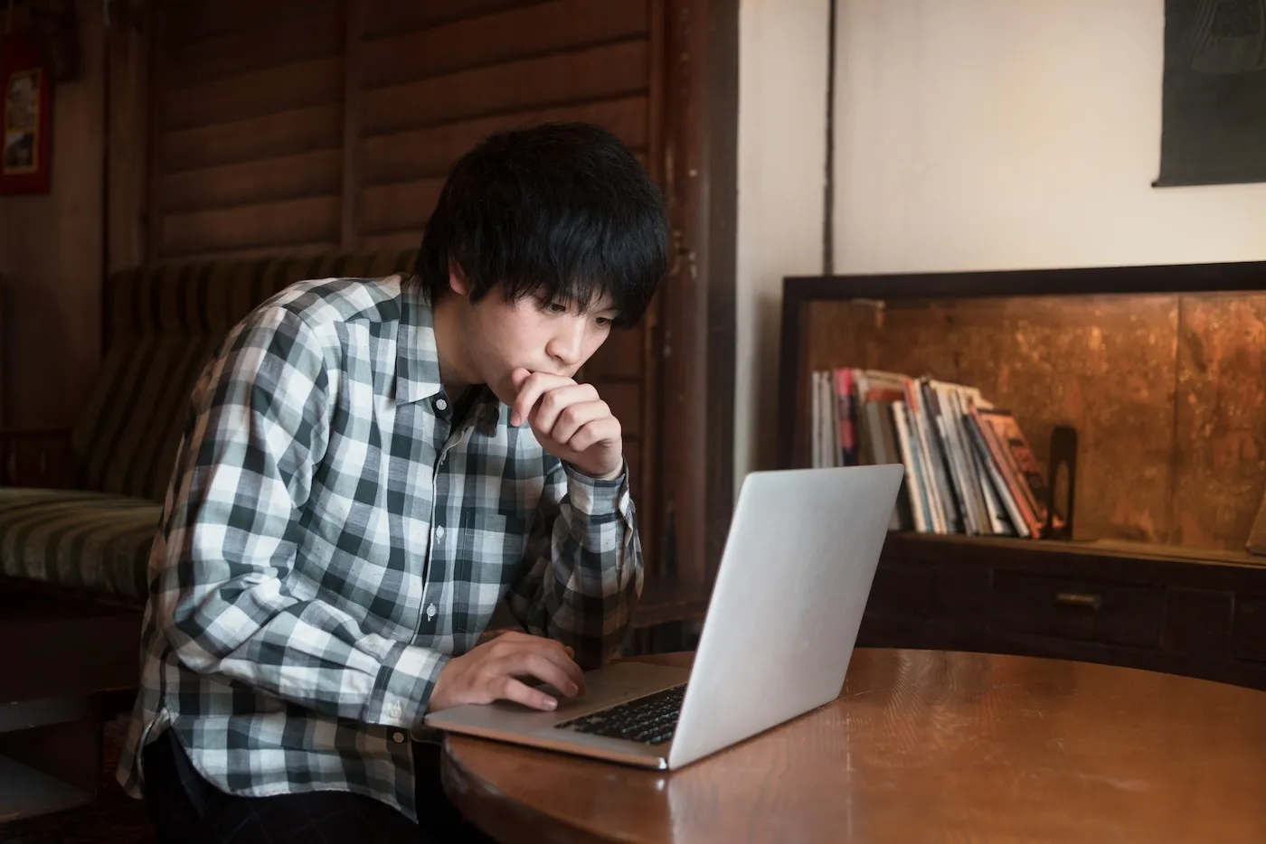 Man sat in a cafe using his computer.