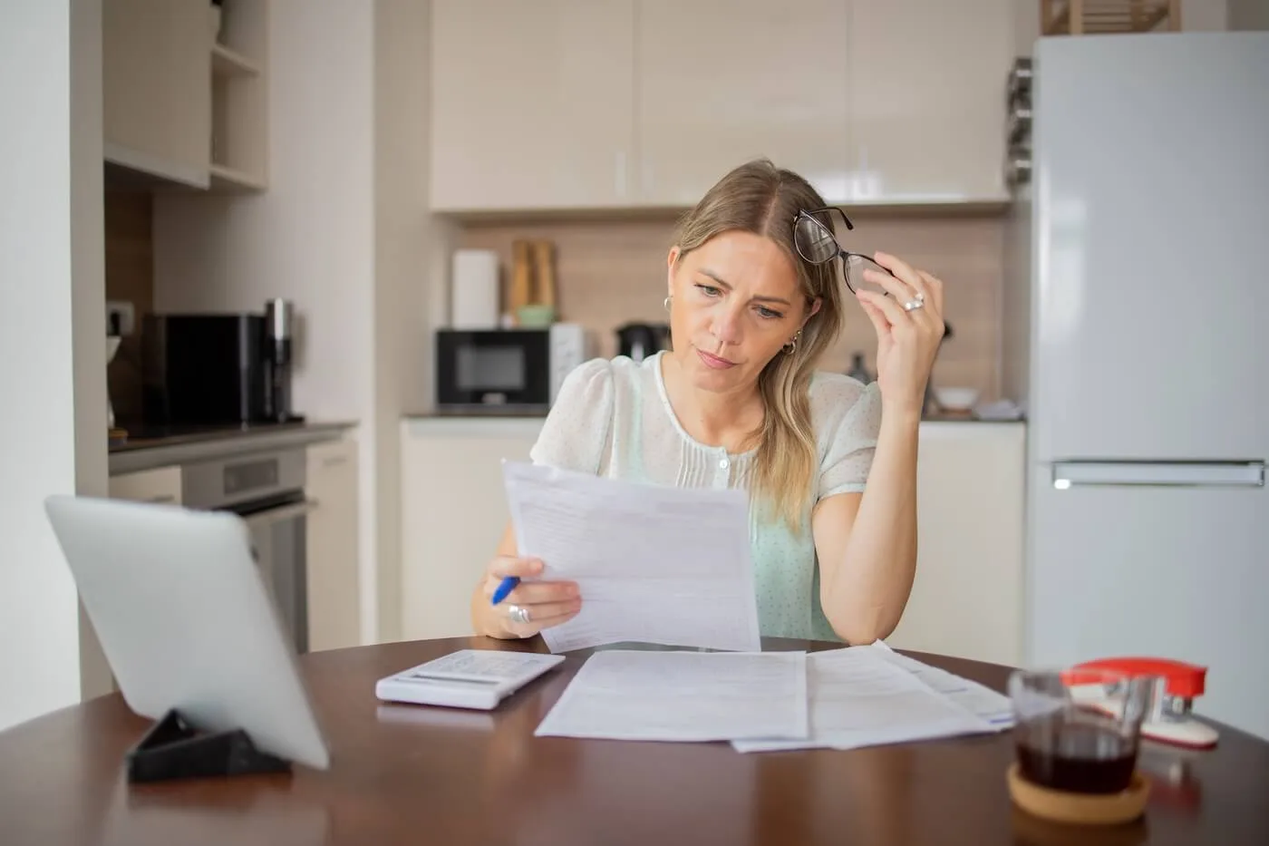 Concerned woman reviewing bank statements in the kitchen