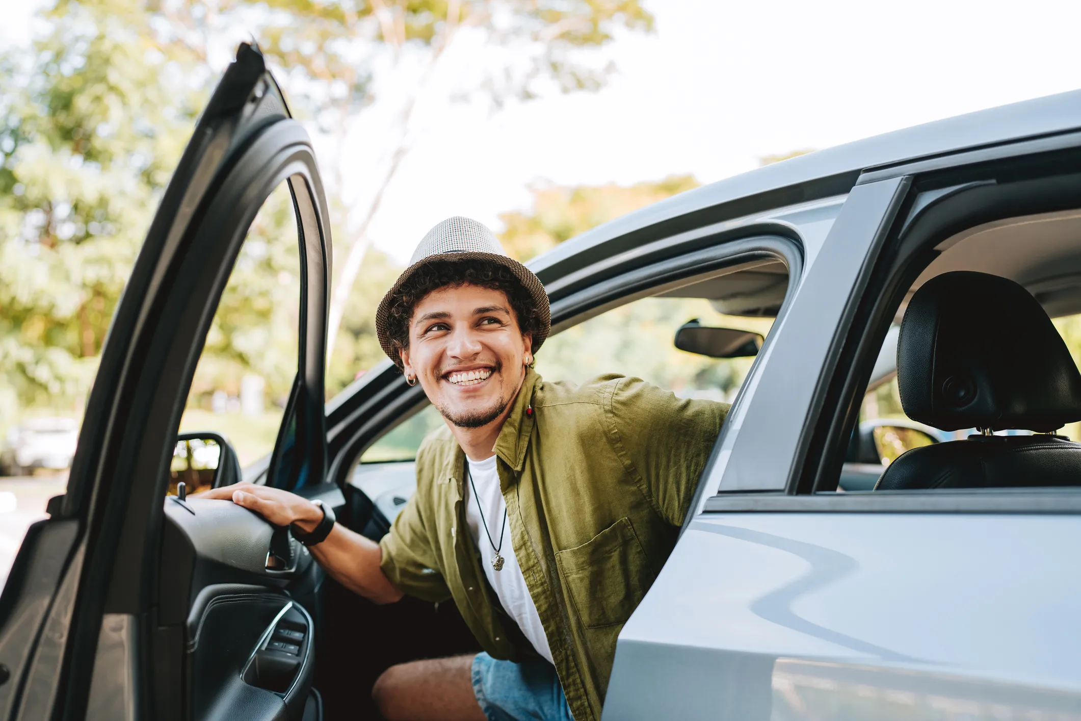 A young smiling man getting out of the car