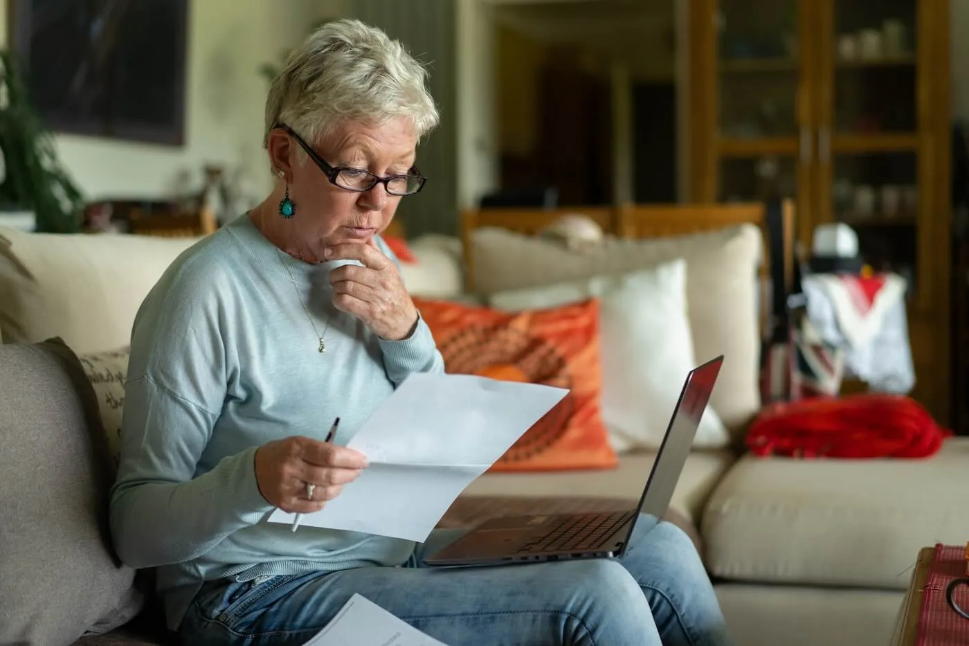 Concerned mature woman with the laptop reviewing the bills in the living room