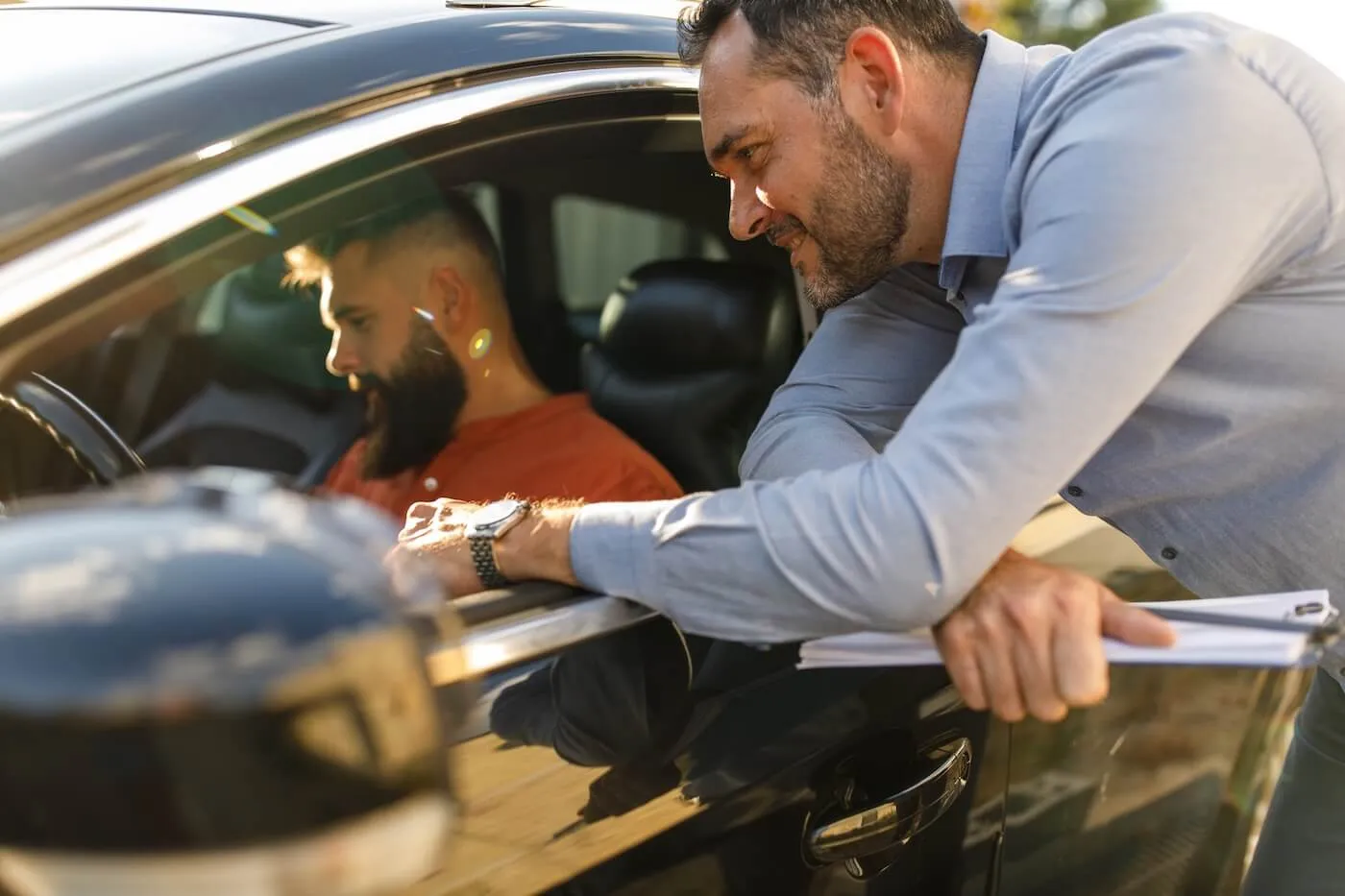 Man is inspecting the car with a male private seller before purchasing it