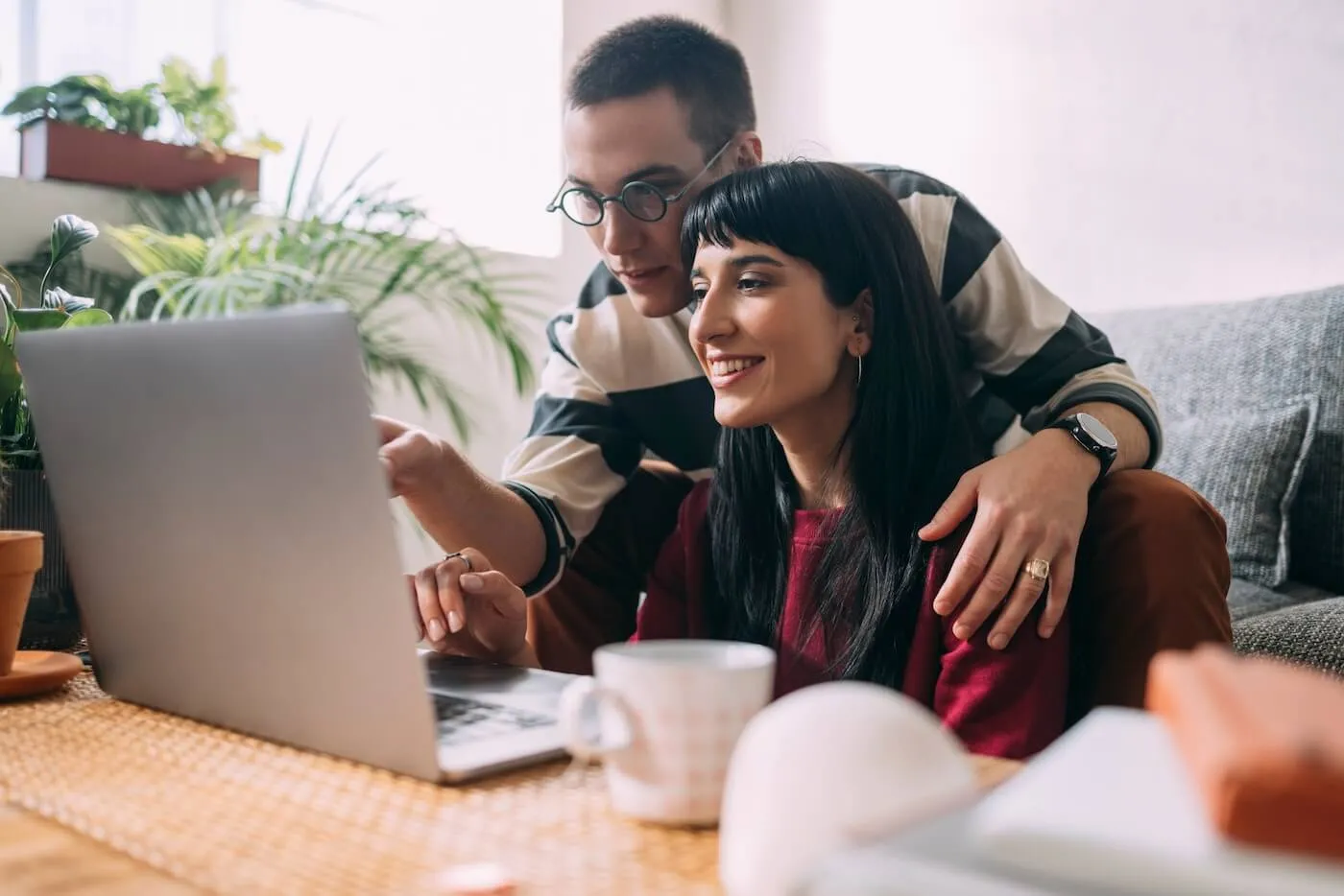 Young couple using a laptop in the living room, man is pointing at the laptop monitor