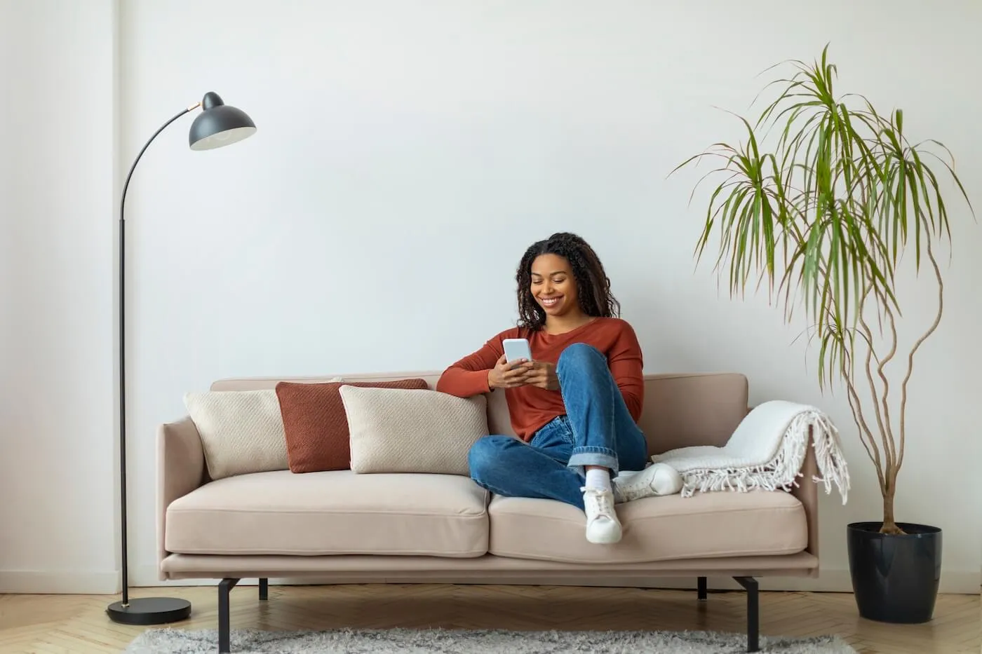 Woman is checking her credit score on smartphone while sitting comfortably on the couch